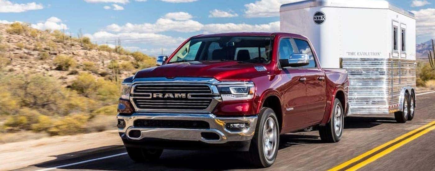 Red 2019 Ram 1500 driving down the road towing a trailer