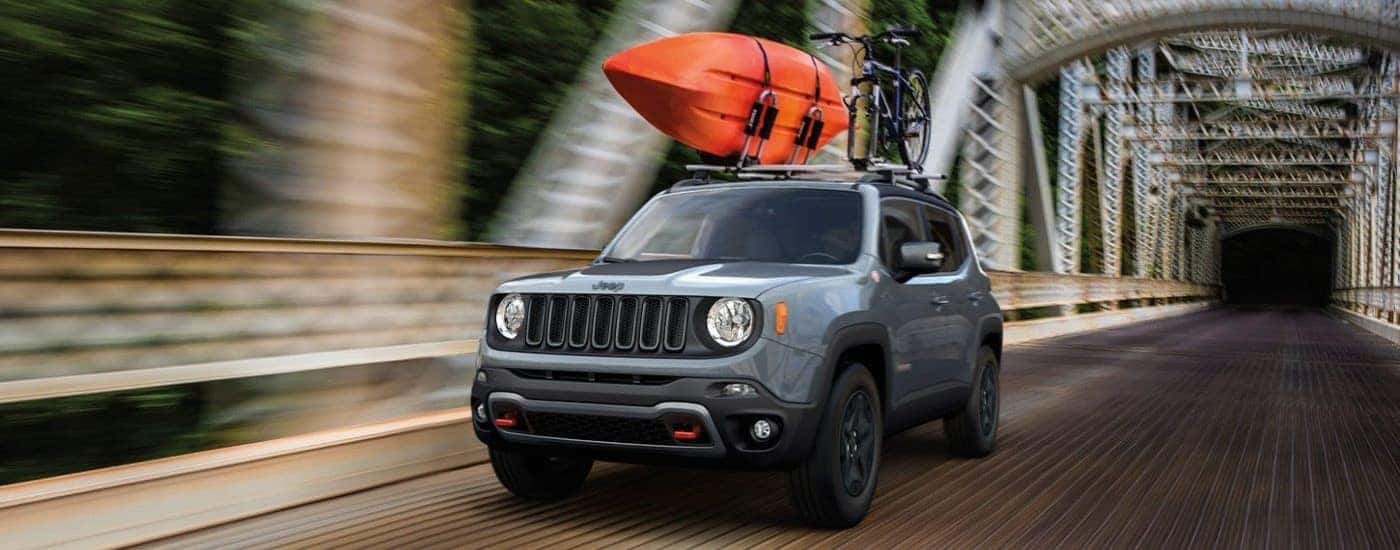 "A grey 2023 Jeep Renegade is shown driving on a bridge.