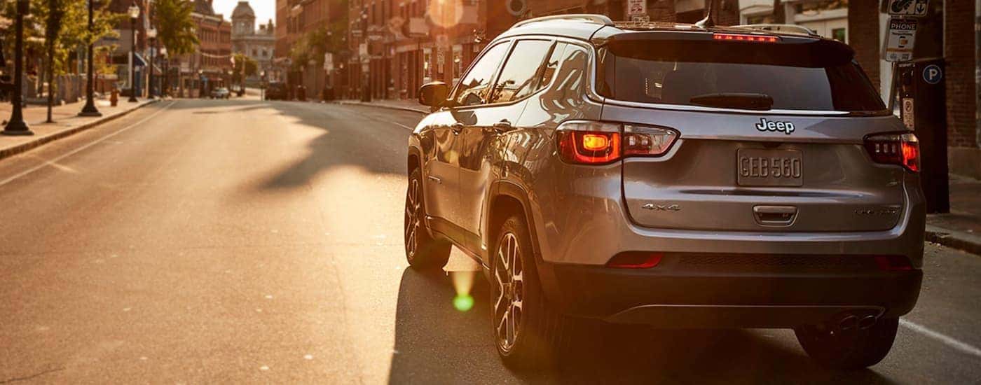 Silver 2021 Jeep Compas from the rear driving on a street