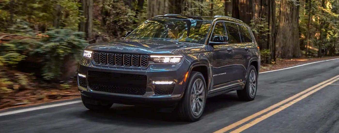Grey 2021 Jeep Grand Cherokee driving down a tree lined road