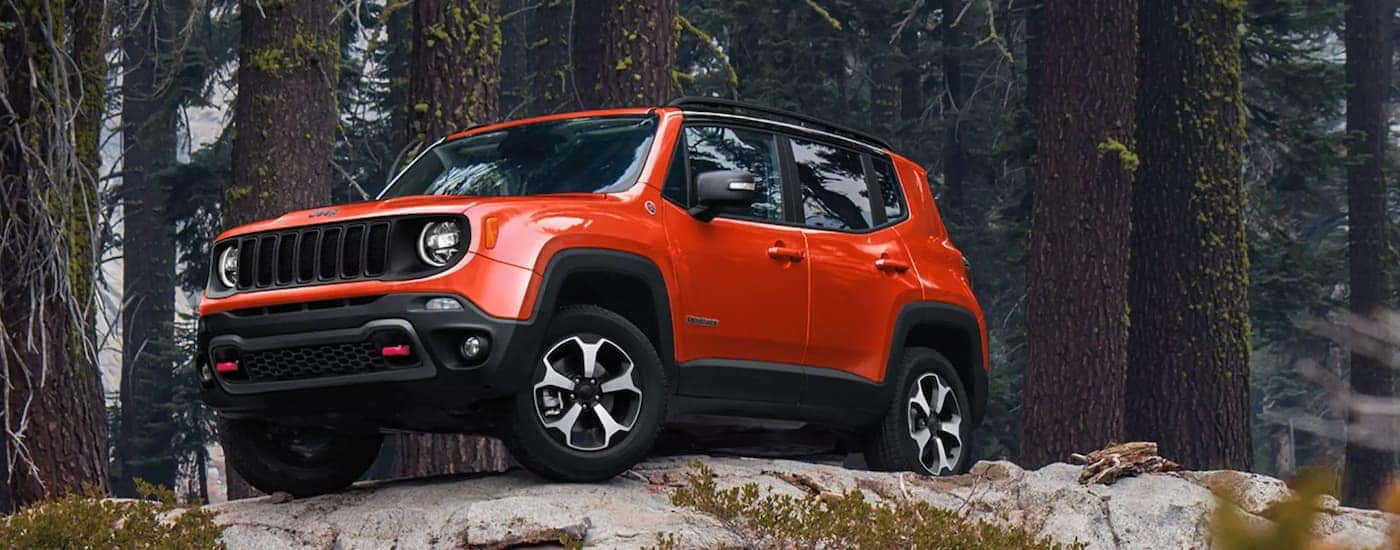 Orange 2021 Jeep Renegade on top of rocks in the woods