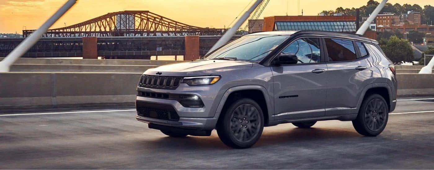 Grey 2022 Jeep Compass driving on a bridge.