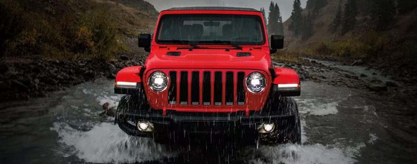 Red 2022 Jeep Wrangler driving through a river