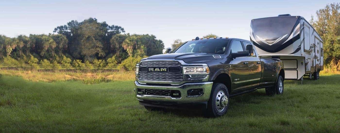 Black 2022 Ram 3500 towing a camper parked in a field