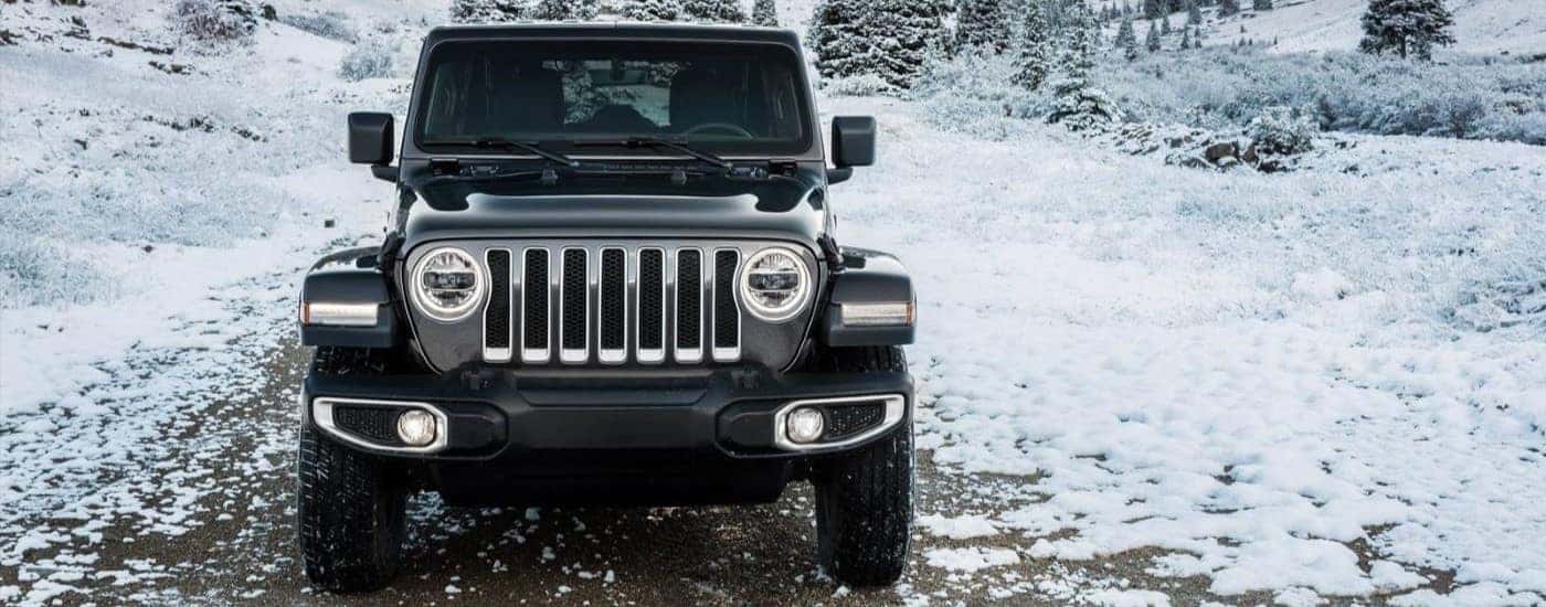 A black 2024 Jeep Wrangler driving down a snowy trail.