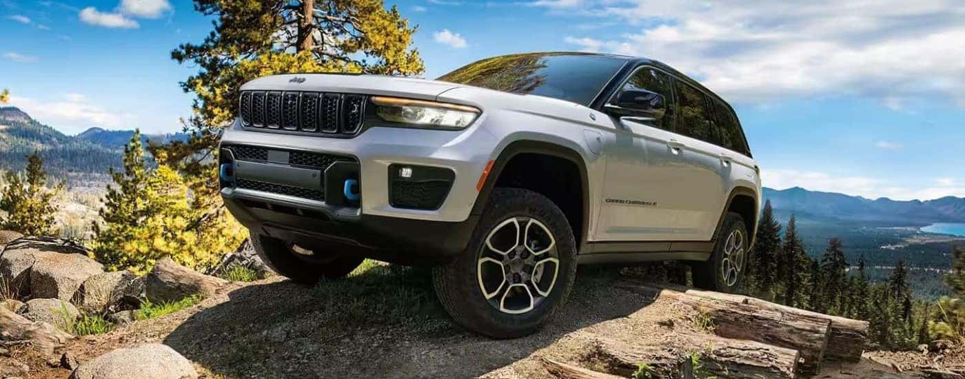 White 2024 Jeep Grand Cherokee driving up a rocky mountain