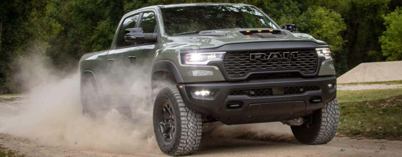 Green 2026 Ram 1500 RHO driving on a dirt road.