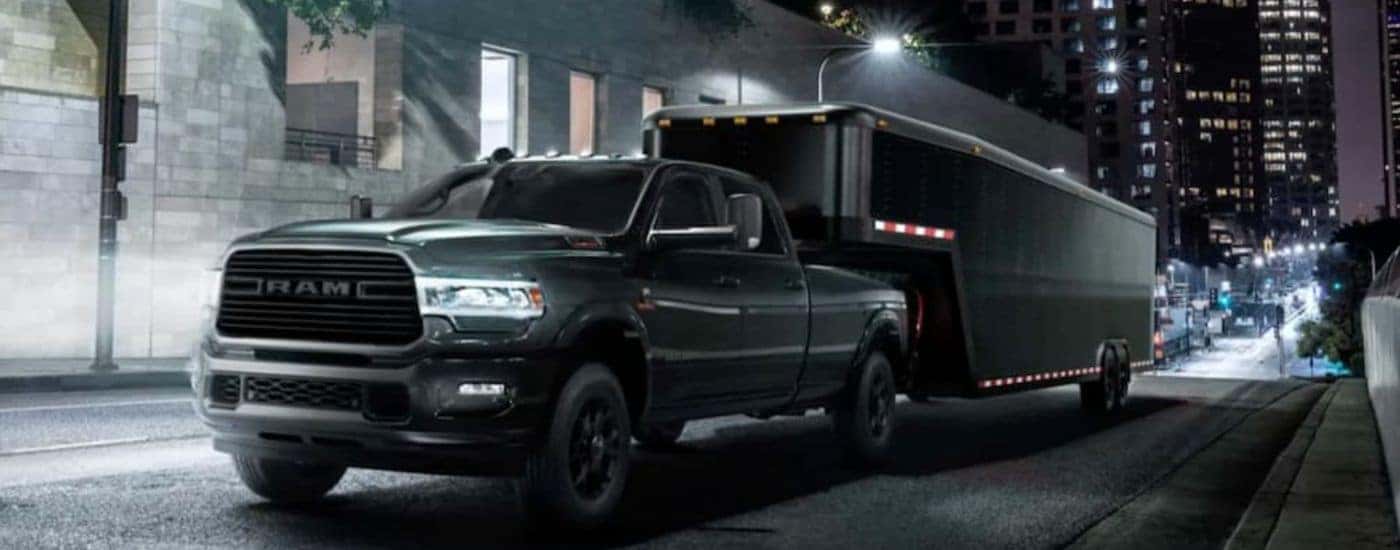 A black 2021 Ram 2500 is shown towing a trailer in a city.