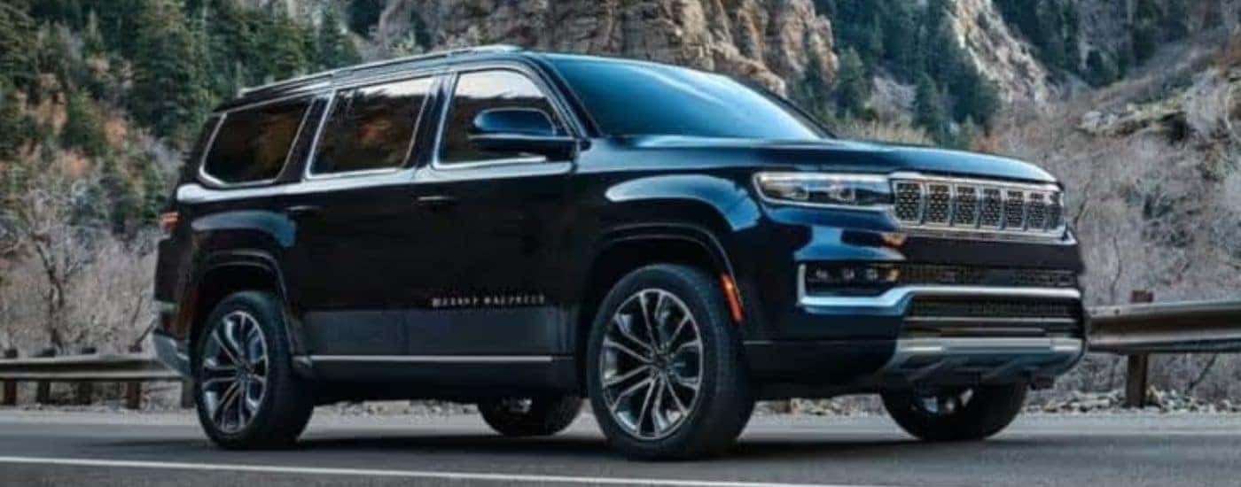 A black 2022 Grand Wagoneer is shown from the side parked in front of a mountain.