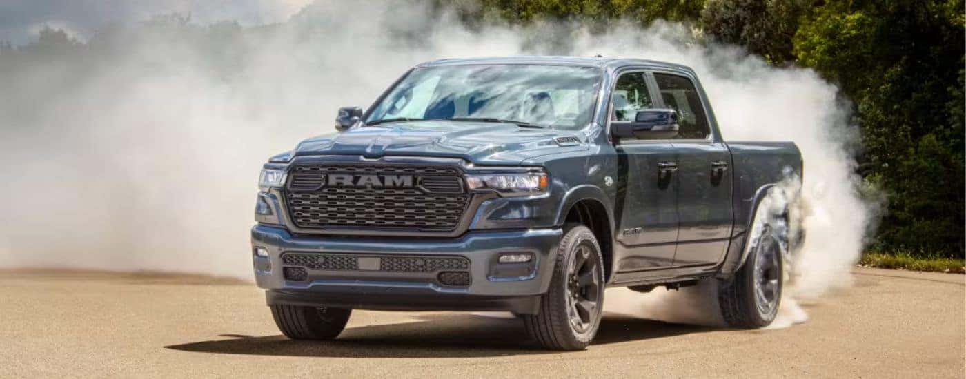 A blue 2026 Ram 1500 shown taking a sharp turn on a sandy lot..