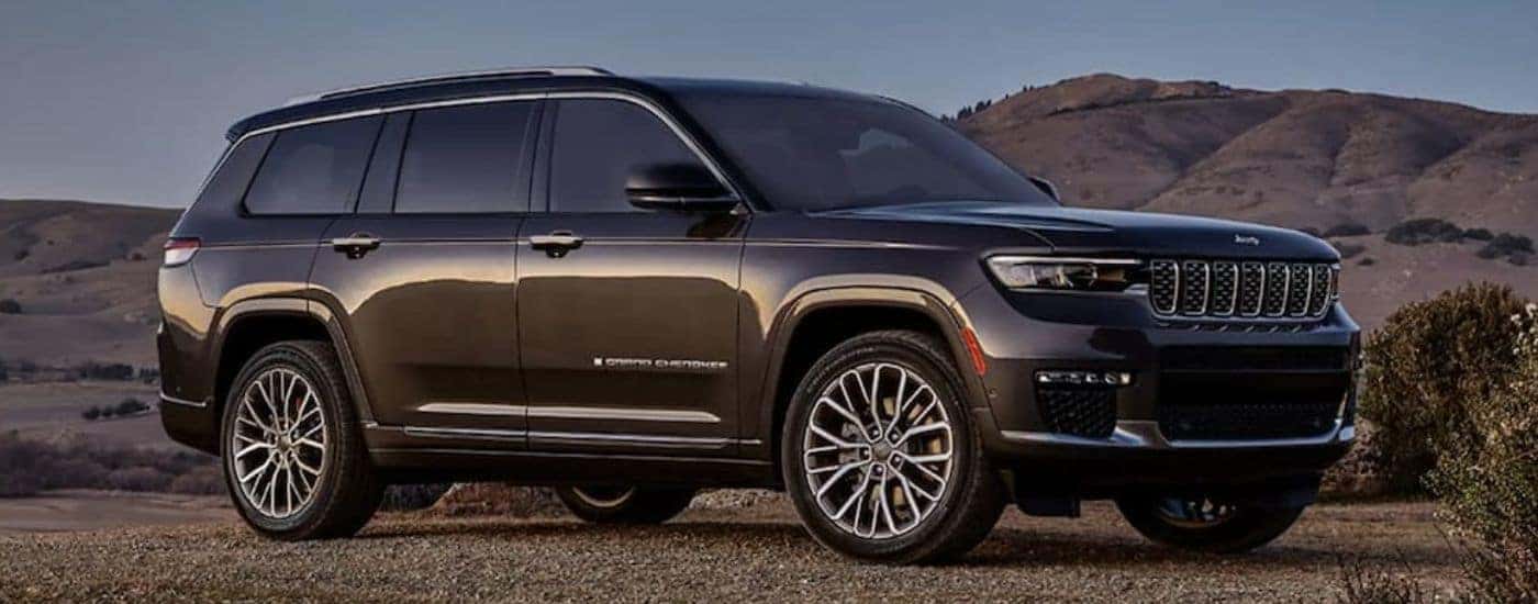 A brown 2023 Jeep Grand Cherokee is shown parked on gravel.