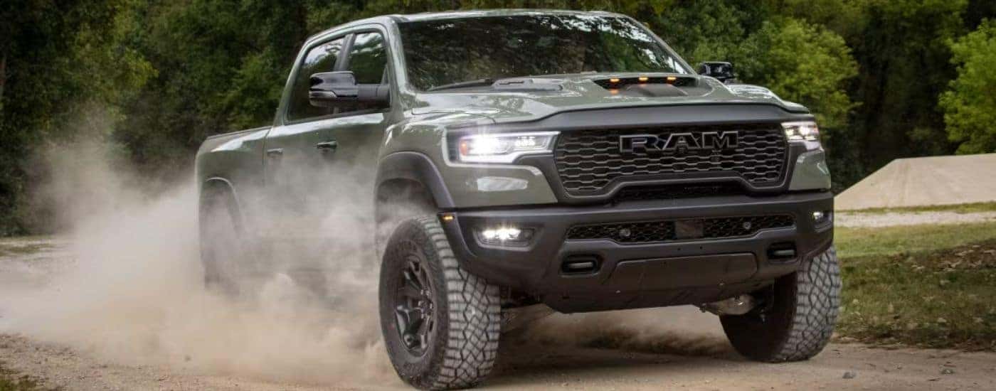 A green 2026 Ram 1500 shown driving on a dirt road.
