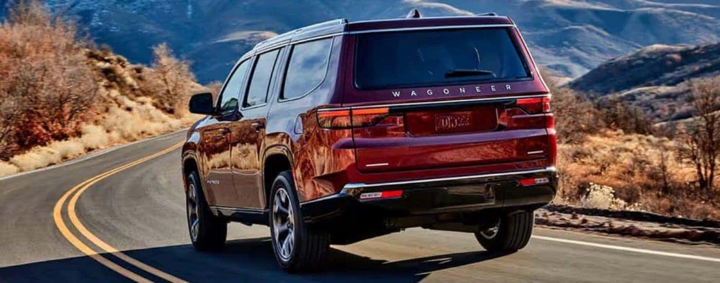 A rear view of a red 2024 Wagoneer driving down a highway.