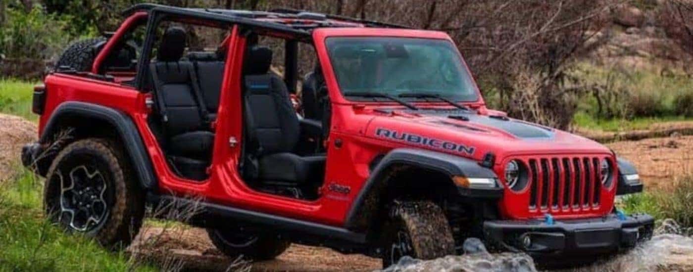 A red 2023 Jeep Wrangler Rubicon 4xe is shown from the side while off-road.