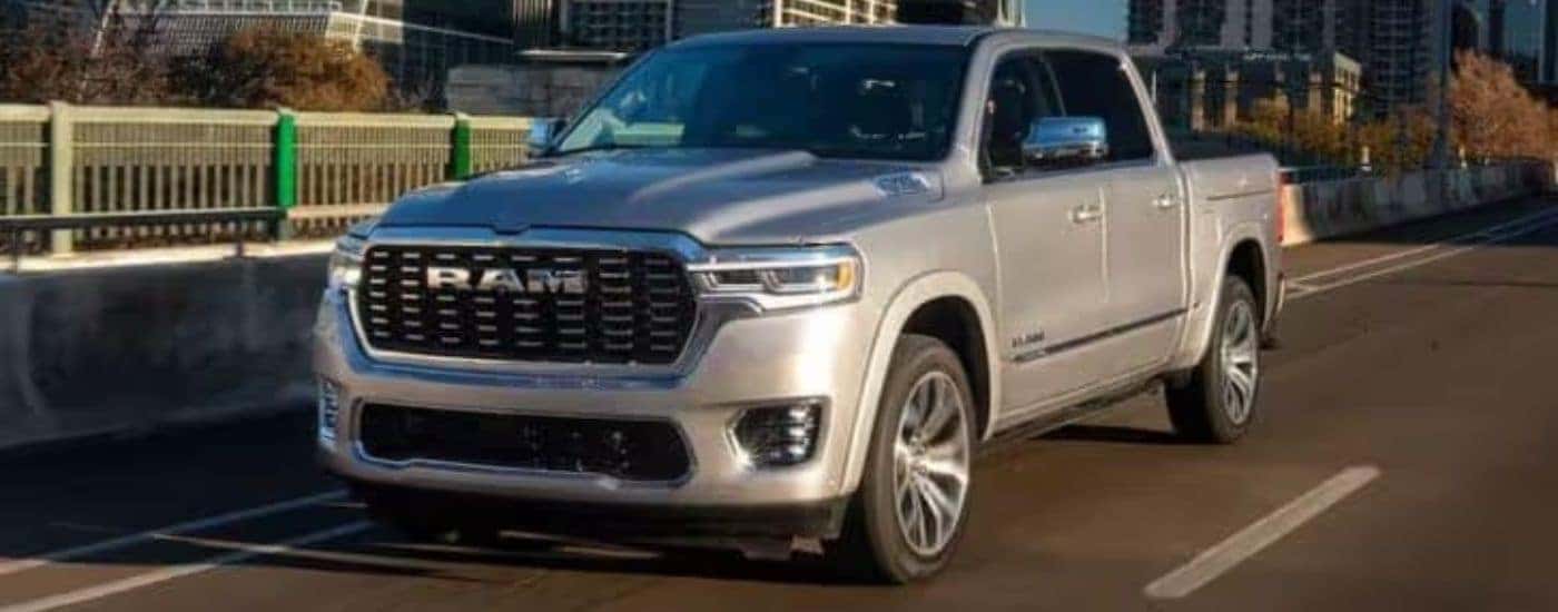 A silver 2025 Ram 1500 is shown driving on a bridge.