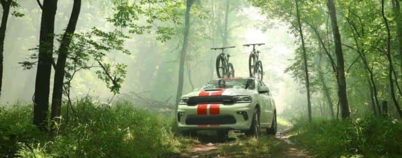 A white 2020 Dodge Durango is shown in the woods with bikes on the roof.