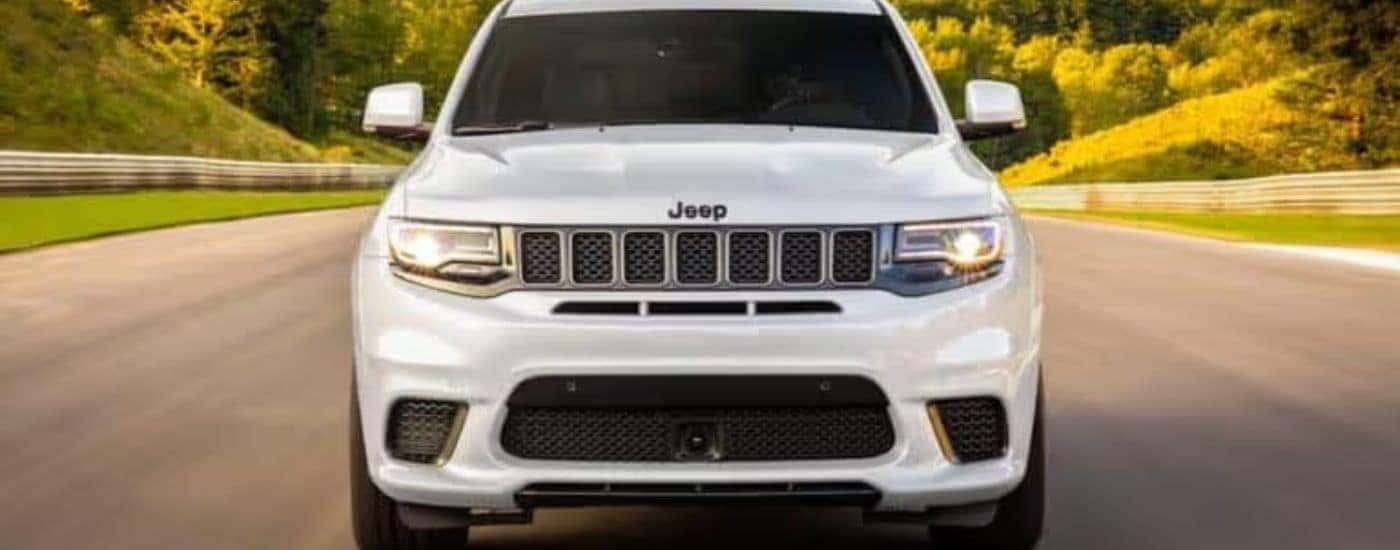 A white 2020 Jeep Grand Cherokee is shown on a race track from the front.