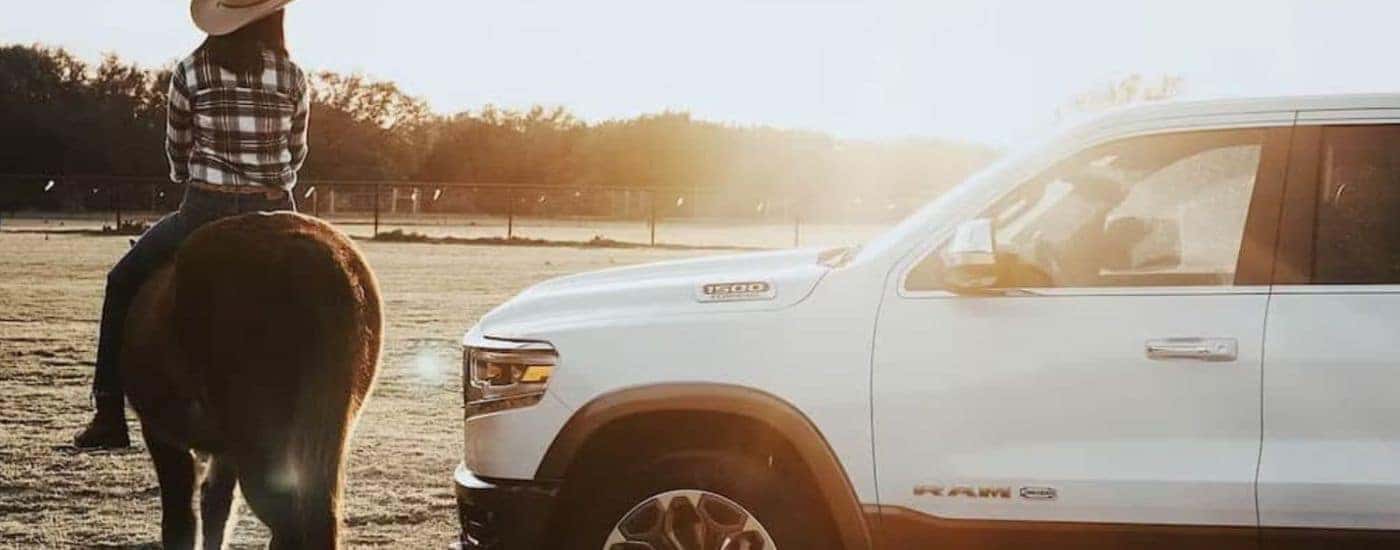 A white 2024 Ram 1500 is shown parked near a person riding a horse.