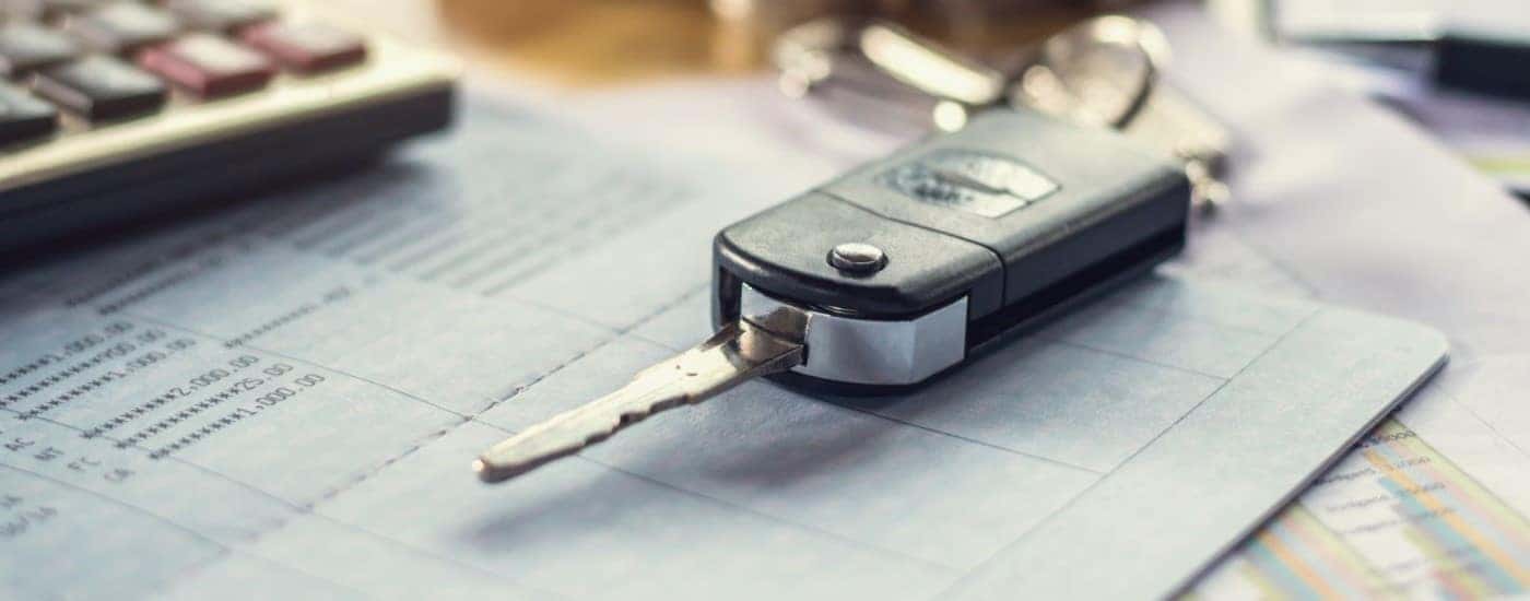 A car key on top of some purchasing paperwork