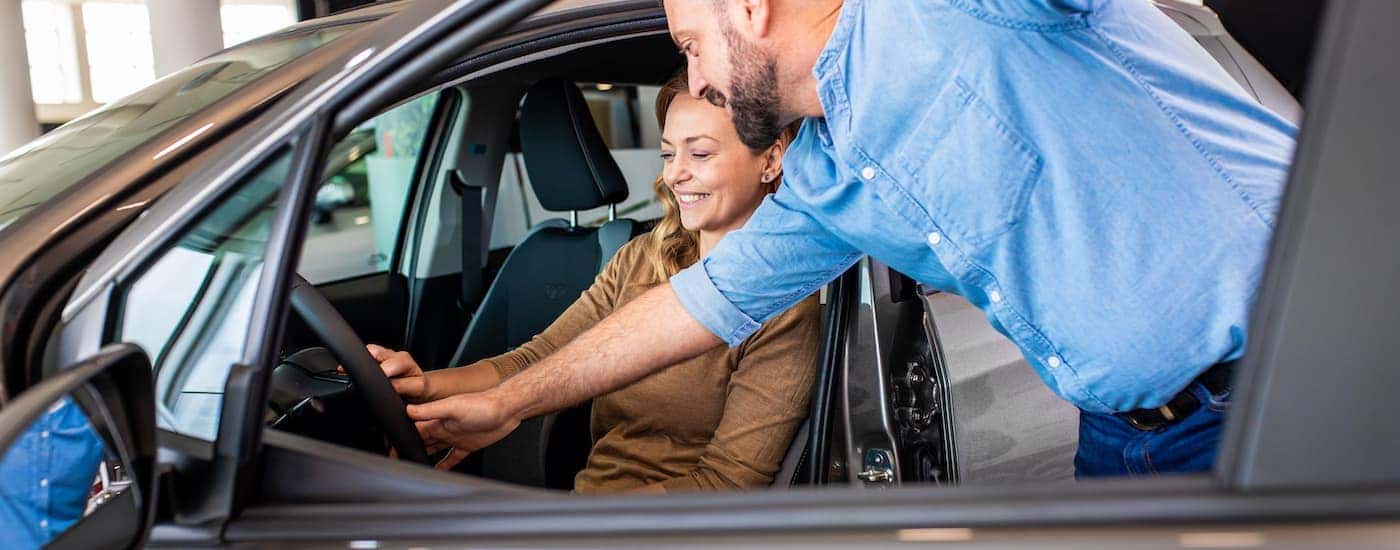A salesperson showing a customer features of a car