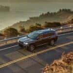 A gray 2026 Jeep Grand Cherokee driving on a highway.