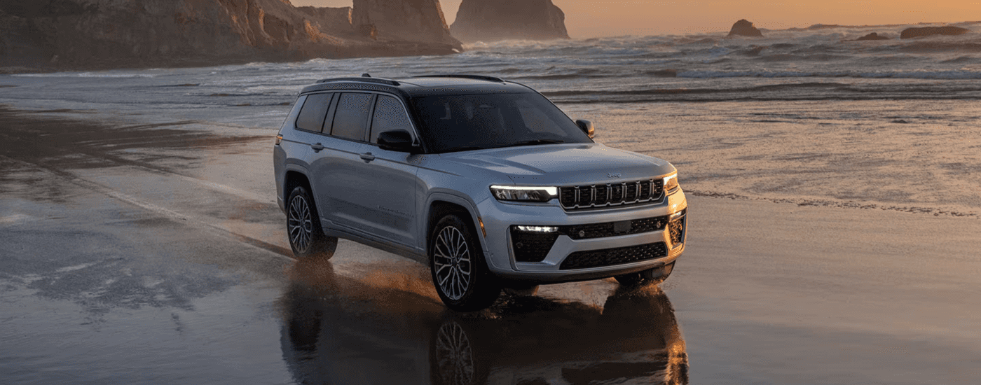 Silver 2026 Jeep Grand Cherokee driving along a beach