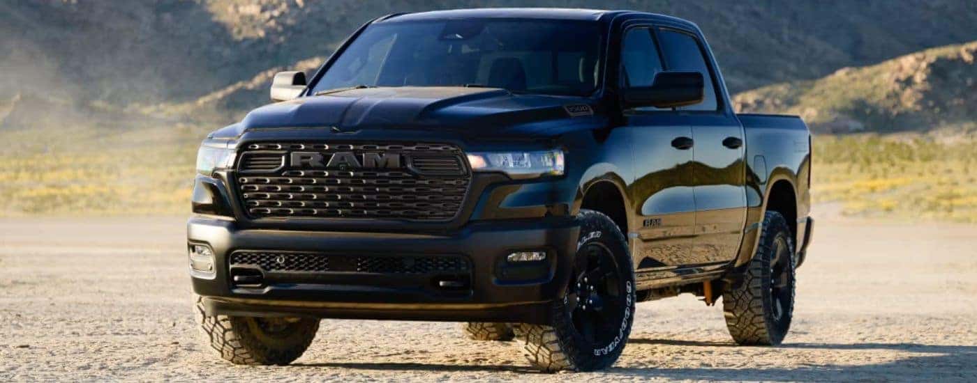 A black 2026 Ram 1500 Warlock 4x4 Crew Cab parked in the desert with mountains in the background.