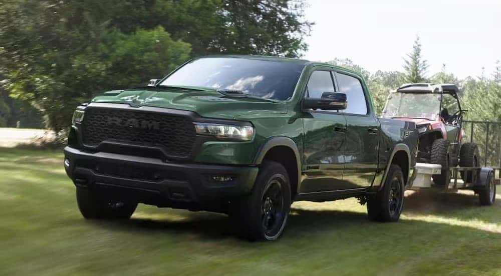 A green 2026 Ram 1500 Rebel towing a trailer.