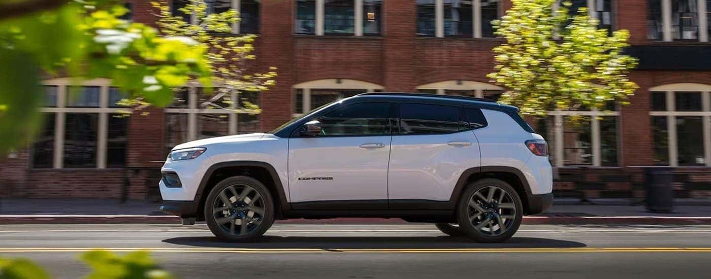 A white 2026 Jeep Compass driving in a city.