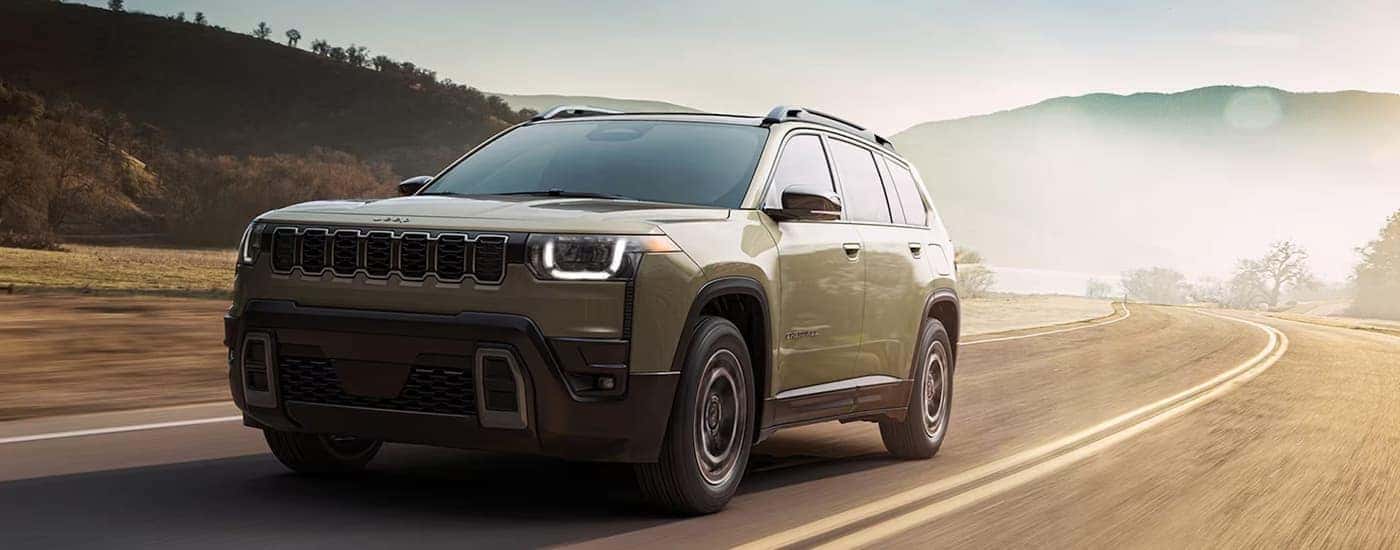 A tan 2026 Jeep Cherokee driving on a highway