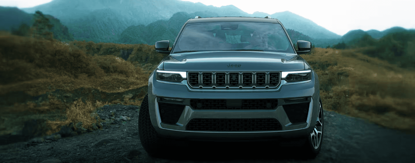 Silver 2026 Jeep Grand Cherokee driving on a hilly road