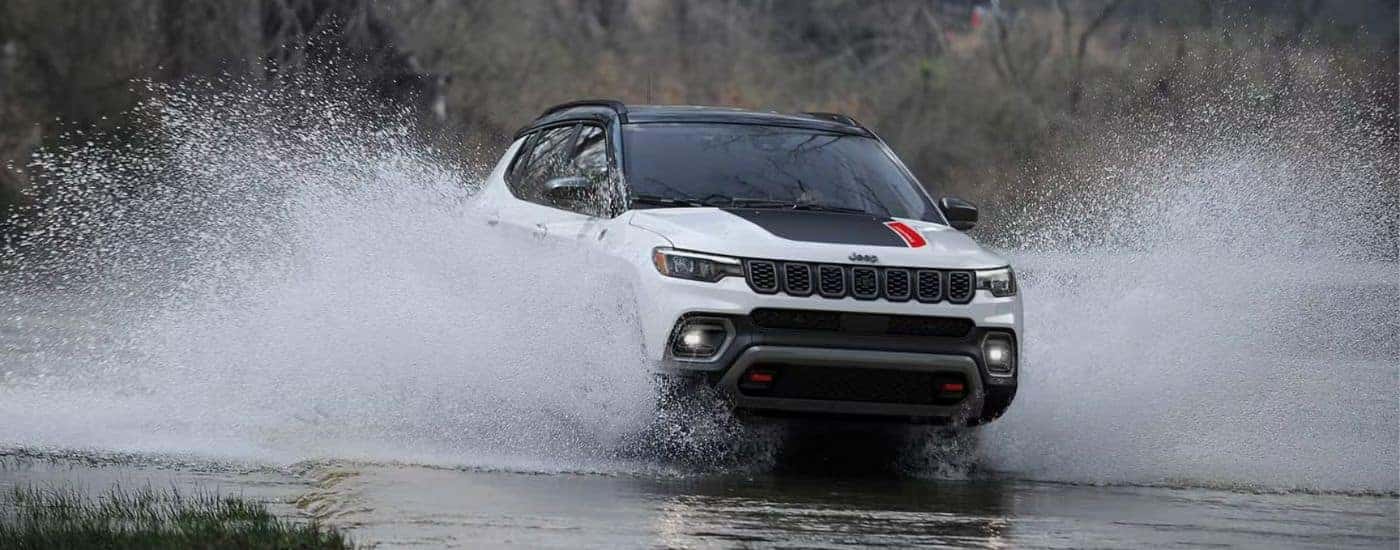 White 2026 Jeep Compass driving through a river.