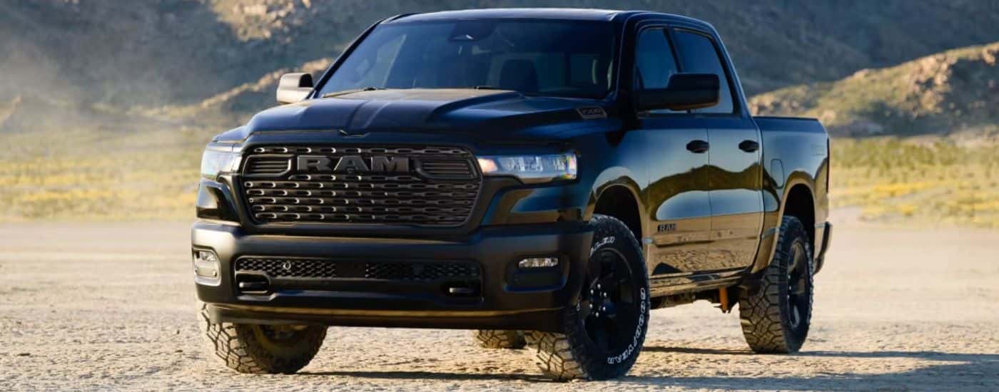 A black 2026 Ram 1500 Warlock 4x4 Crew Cab parked in the desert with mountains in the background.