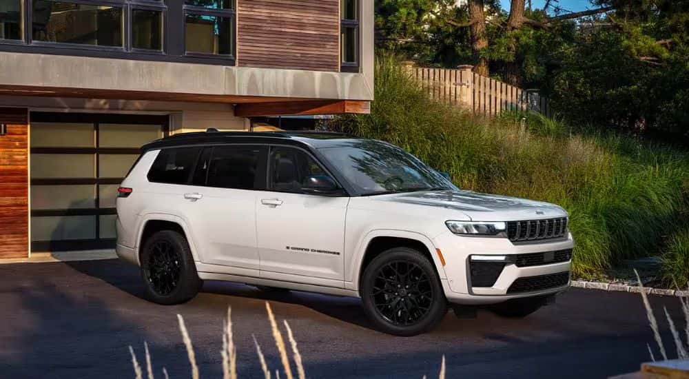 A white 2027 Jeep Grand Cherokee L parked in a driveway.