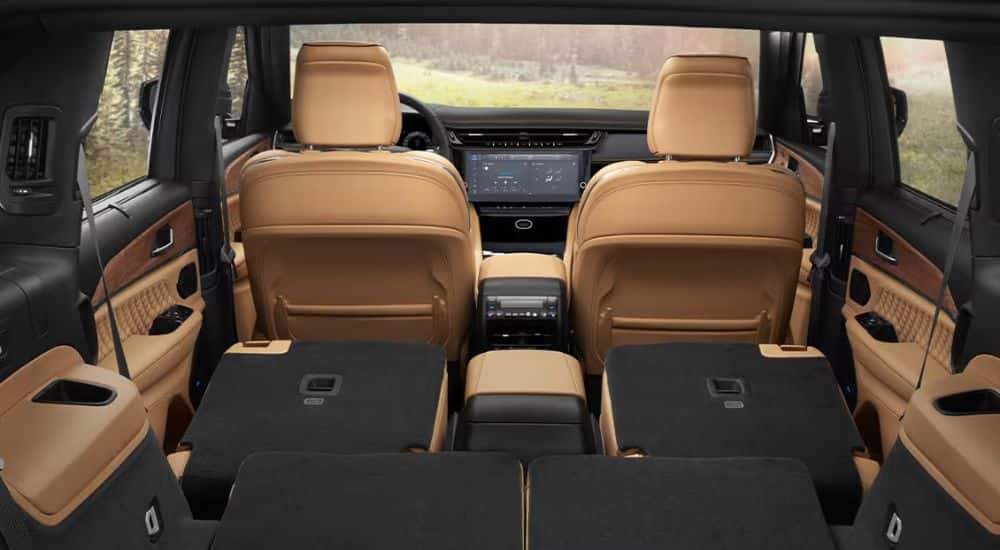 Black and tan interior of a 2027 Jeep Grand Cherokee L with rear seats folded down.